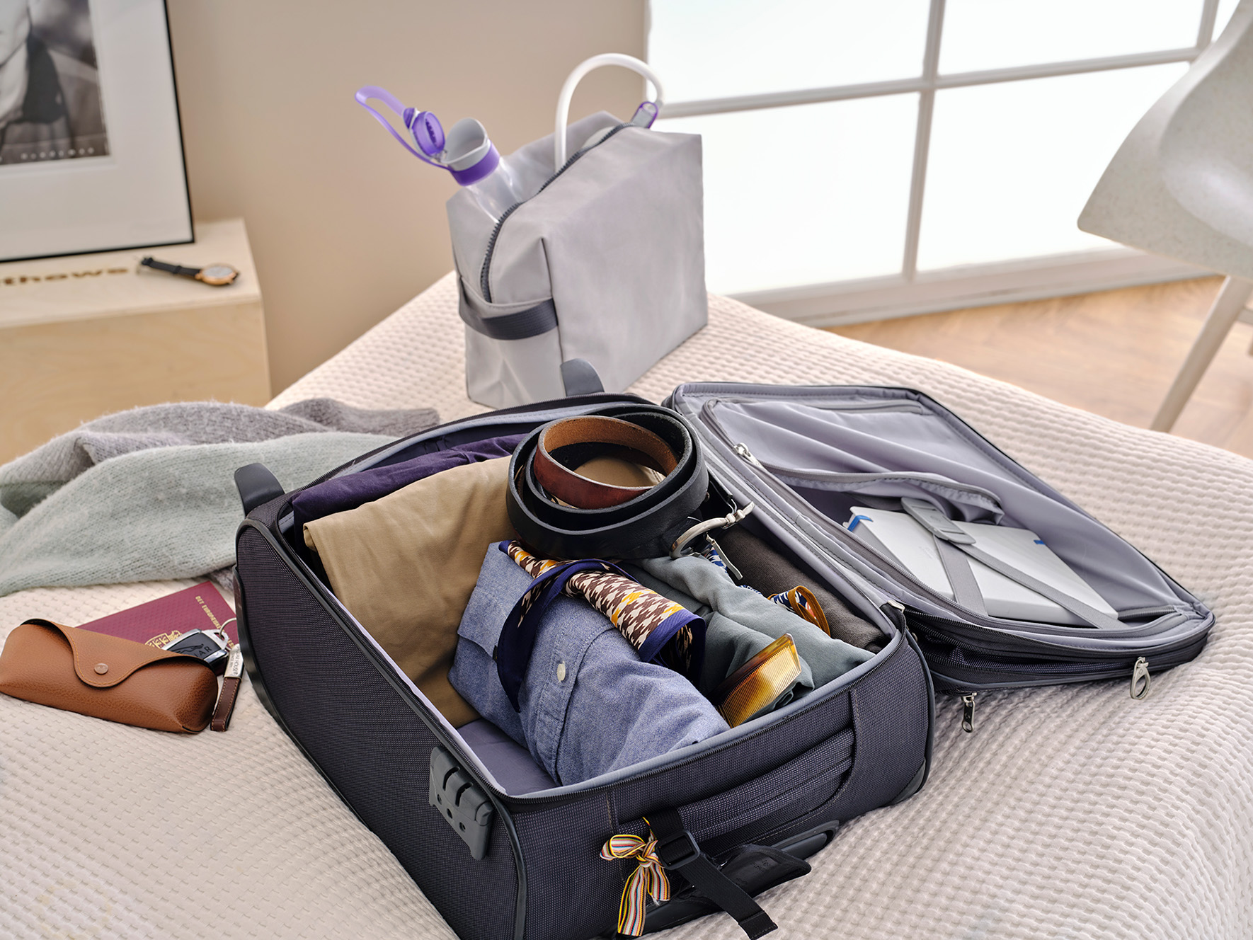 Qufora Irrisedo Flow packed in a toiletbag standing on a bed next to a filled suitcase