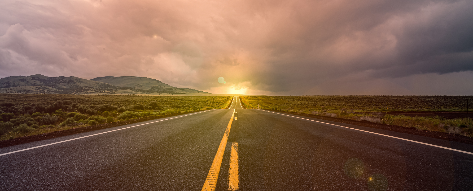 Landscape with a road and fields and a sunset in the horizont
