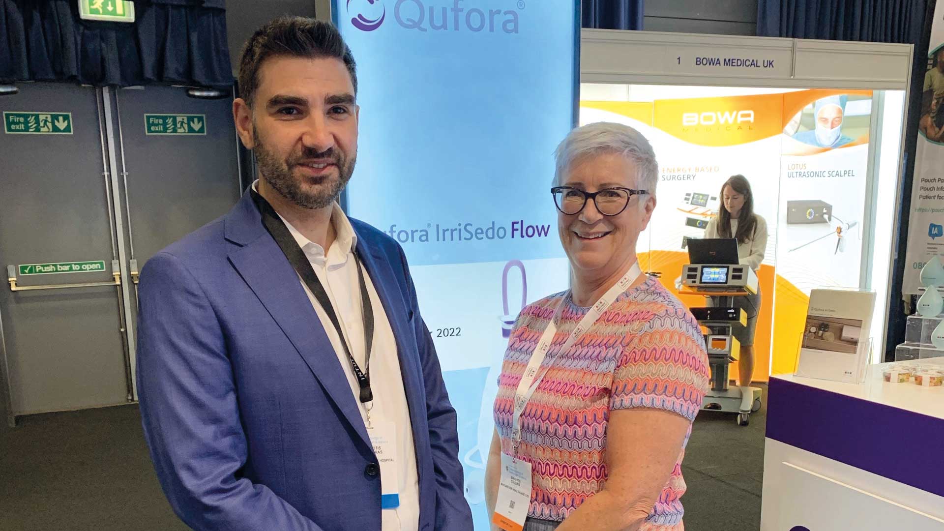 Man and woman at a conference, smiling at the camera