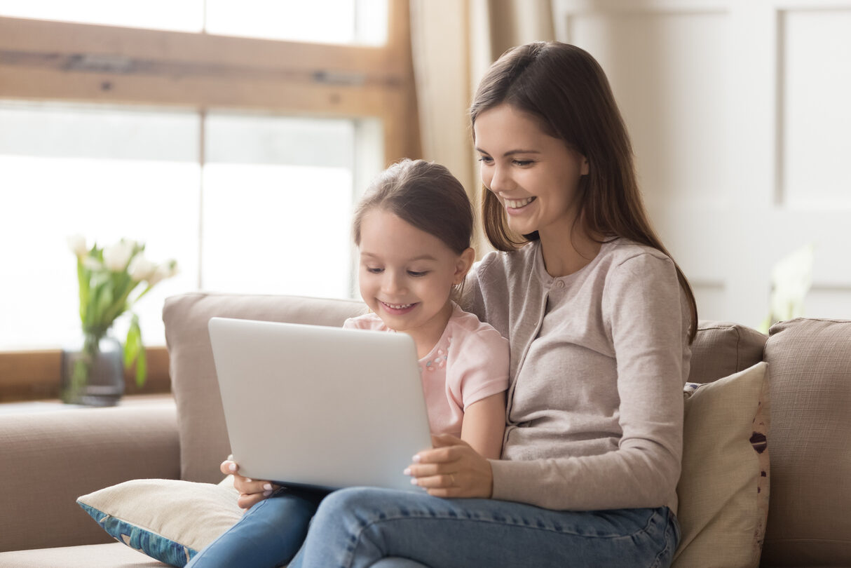 Happy mother and child daughter use laptop computer at home