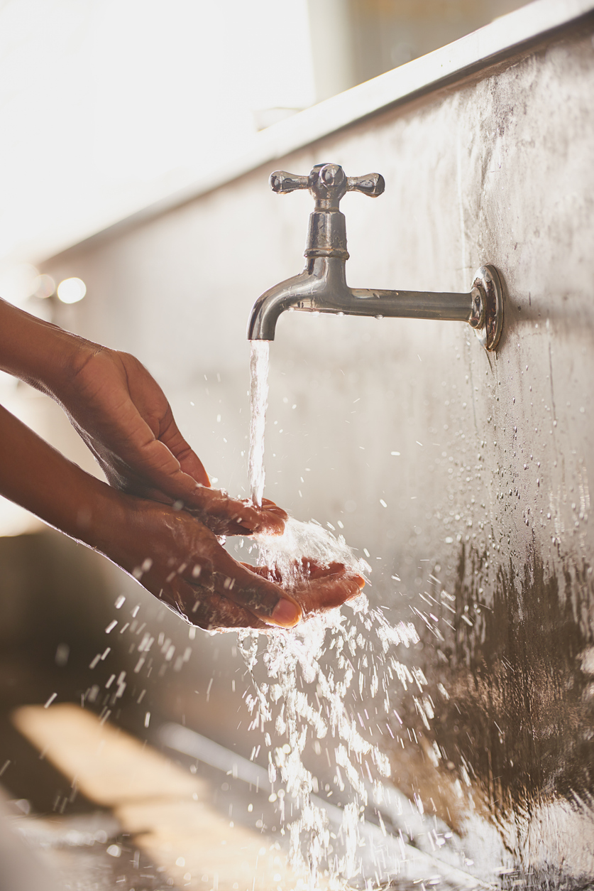 Close-up of a woman washing her hands under a faucet